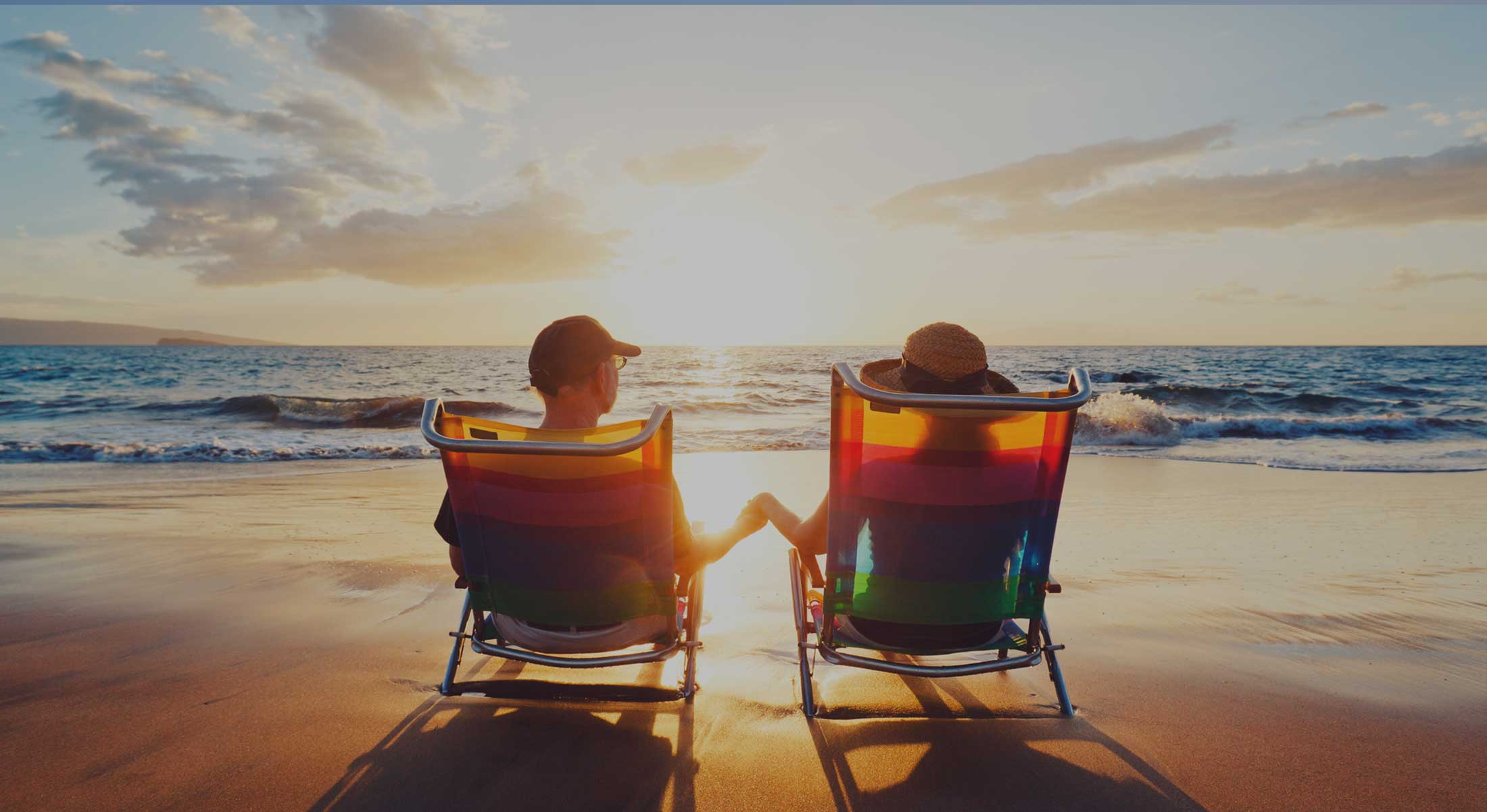 Couple sitting in beach chairs looking over ocean with sun rising.