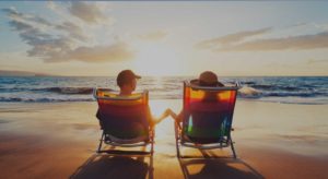 Couple in beach chairs looking into ocean during sunrise